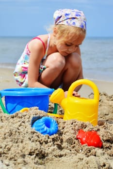 Little girl playing on the sand beach.
