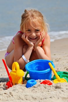 Little girl playing on the sand beach.