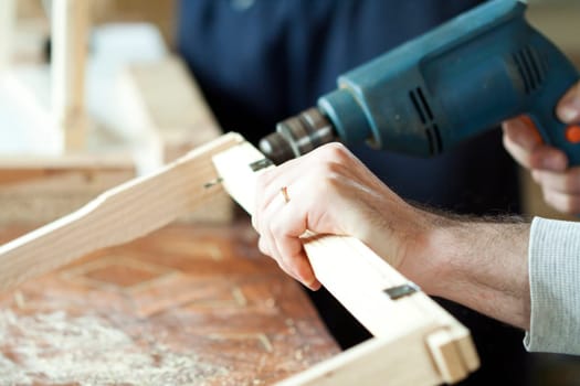 Man's arms drill lath in the workshop.