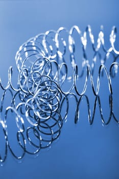 two interlocking chrome spirals bent on a blue background