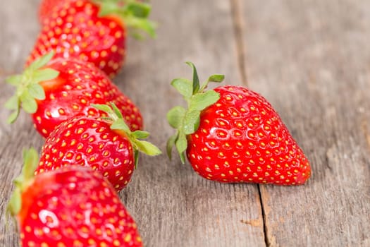 Fresh strawberries in a row on wooden background