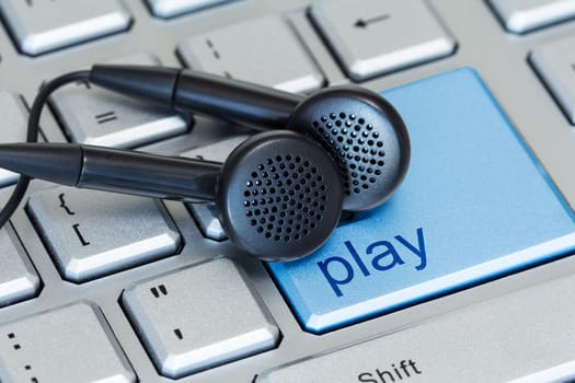 Earphones on computer keyboard with a play button