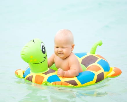 Baby bathing in the sea with swim ring