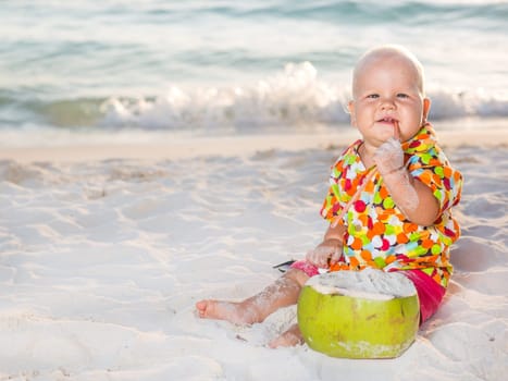 Funny baby with coconut on the beach
