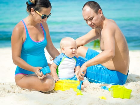 Parents and baby playing together on the beach