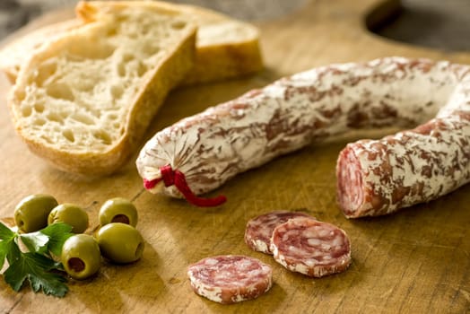 Ring salami with baguette and green olives