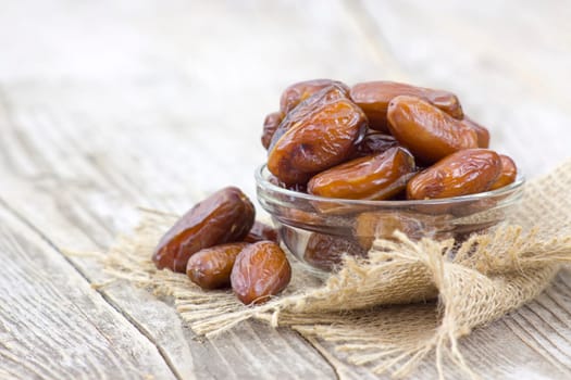 dried dates in a bowl on wooden background