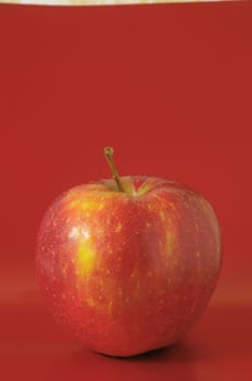 One Juicy Hot Red Apple over a Colored Background