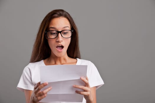 brunette young woman realizes that something amazing happened reading a white letter or document