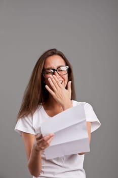 a long haired brunette reading something moving on a white document or letter and laughing or smiling