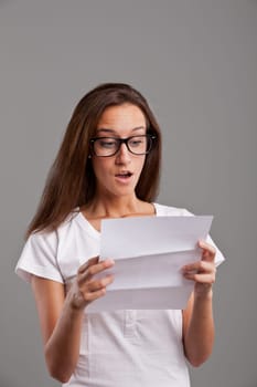 brunette young woman realizes that something amazing happened reading a white letter or document