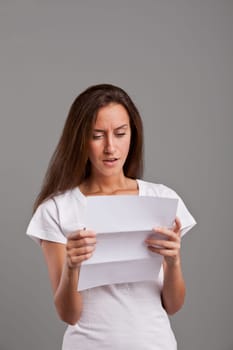 brunette young woman realizes that something wrong happened reading a white letter or document