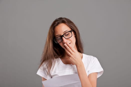 brunette young woman with glasses realizes that someone loves her reading a white letter or document