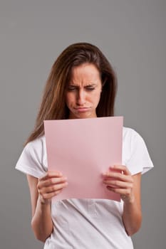 girl pouts because she read something bad on a pink document maybe by a lover or a money loss
