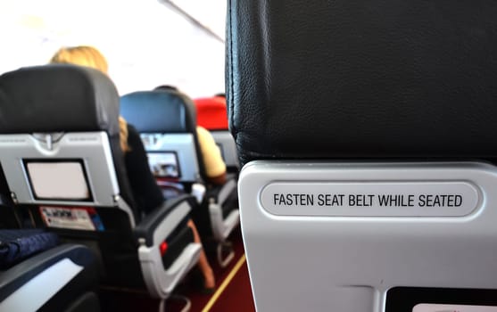 airplane seat with fasten seat belt while seated text