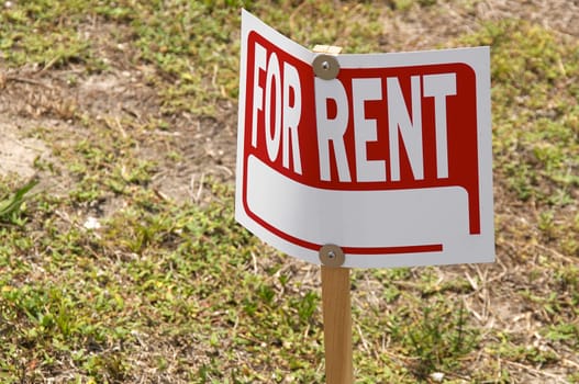 A blank For Rent Sign is screwed to a wooden post and is outside on the lawn.