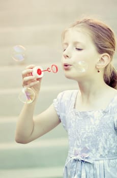 Retro styled photo of young girl blowing soap bubbles