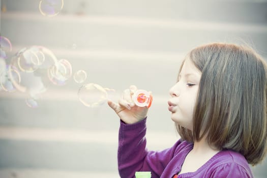 Retro styled photo of young girl blowing soap bubbles