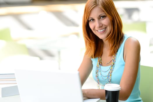 Smiling student girl with laptop at college looking at camera