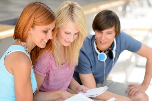 Three college friends studying together looking into book summer time