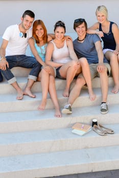 Full length of happy college students sitting together on campus  stairs