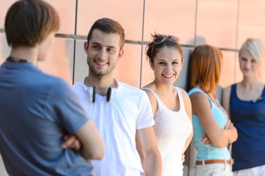 Group of friends students in row leaning against modern college wall