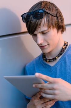 Student boy looking at tablet leaning against wall