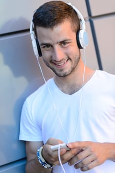 Student boy with headphones by modern wall smiling at camera