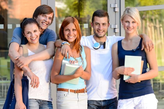 Group of smiling students standing front of college campus summer