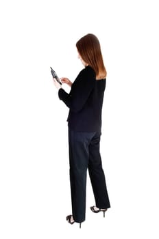 A tall slim young business woman standing in a black suit from the back,.dialling on the phone, isolated for white background..