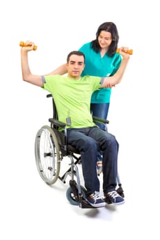 Physical therapist works with patient in lifting hands weights. Young adult in wheelchair.