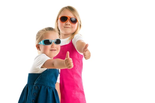 two little girls showing thumbs up. Studio shot.