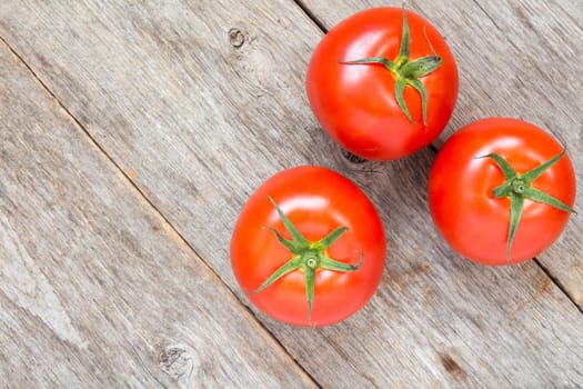 Three fresh red tomatoes on wooden background