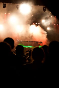 Cheering crowd in front of bright colorful stage lights