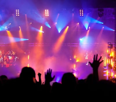 Cheering crowd in front of bright colorful stage lights