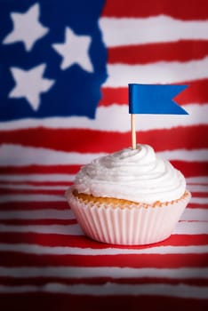 Cupcake with white Topping and Blue Flag with Copyspace for Your Text in front of an American Flag like Background