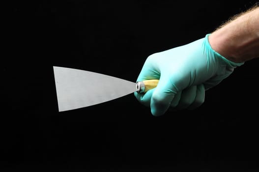 One Spatula and a Hand on a Black Background