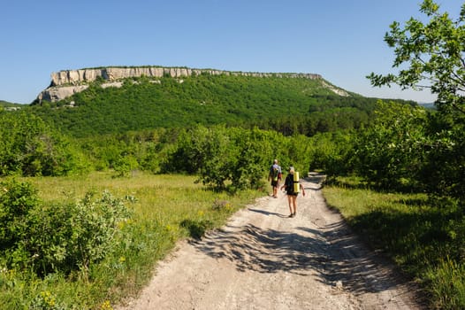 two people traveling with backpacks, walking on the road