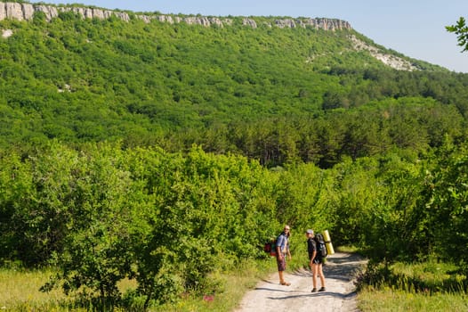 two people traveling with backpacks, walking on the road
