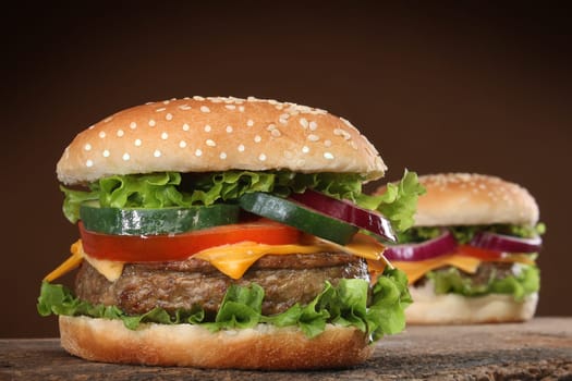 Two delicious hamburgers on wood background.