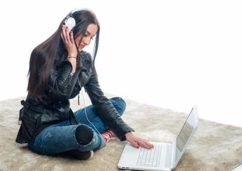 Young woman with laptop and headphones sits on the floor