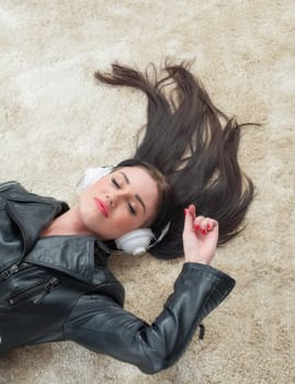Young woman lies on the floor listening to music