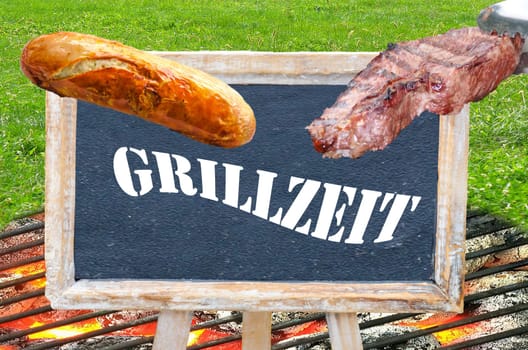 Table with inscription Grillzeit with grilled sausage and steak over charcoal fire