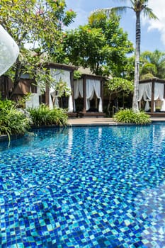 Swimming pool in a tropical resort on holiday with palm trees in the sunshine outdoors