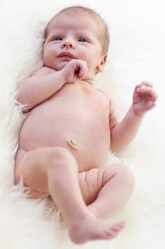 Little baby toddler newborn naked on a white fur as Detal