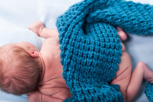 Newborn baby wrapped in a scarf sleeps naked as a close-up