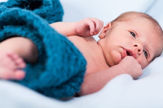Newborn baby wrapped in a scarf sleeps naked as a close-up