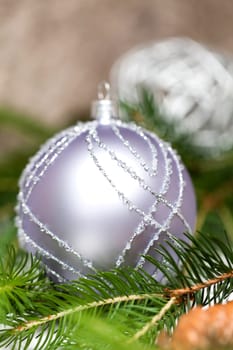 Silver Christmas tree balls in green fir branches with white shiny snow as macro detail
