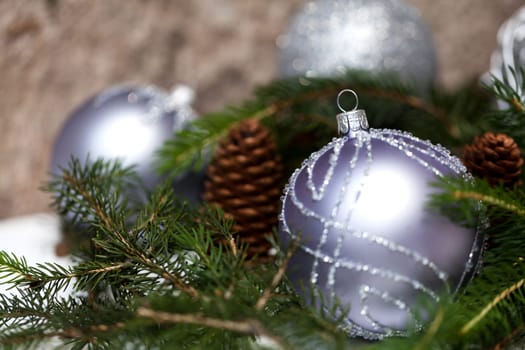 Silver Christmas tree balls in green fir branches with white shiny snow as macro detail