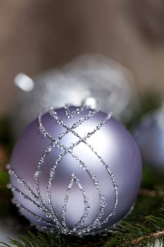 Silver Christmas tree balls in green fir branches with white shiny snow as macro detail